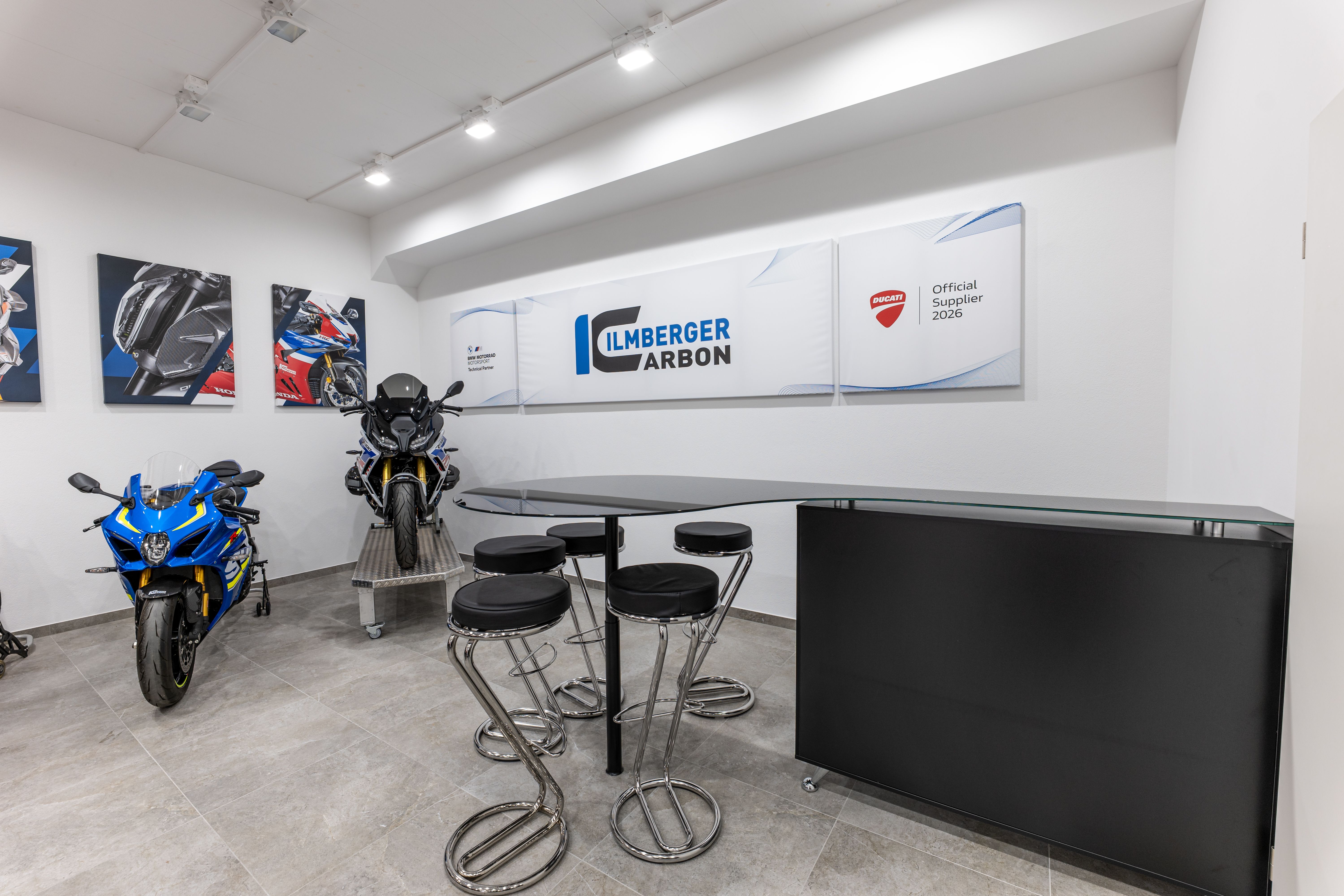 Pièces de carénage en carbone d’Ilmberger Carbon dans le showroom à côté d’une moto de course Showroom4.jpg